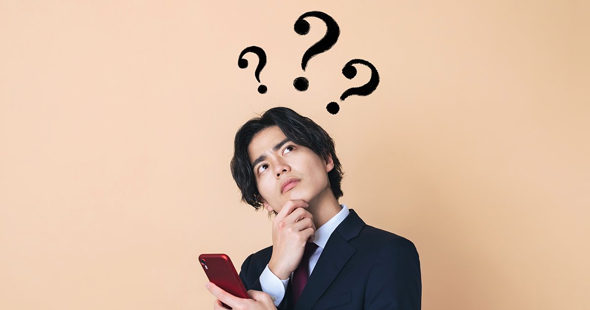 スマホを持って考える若いビジネスマン