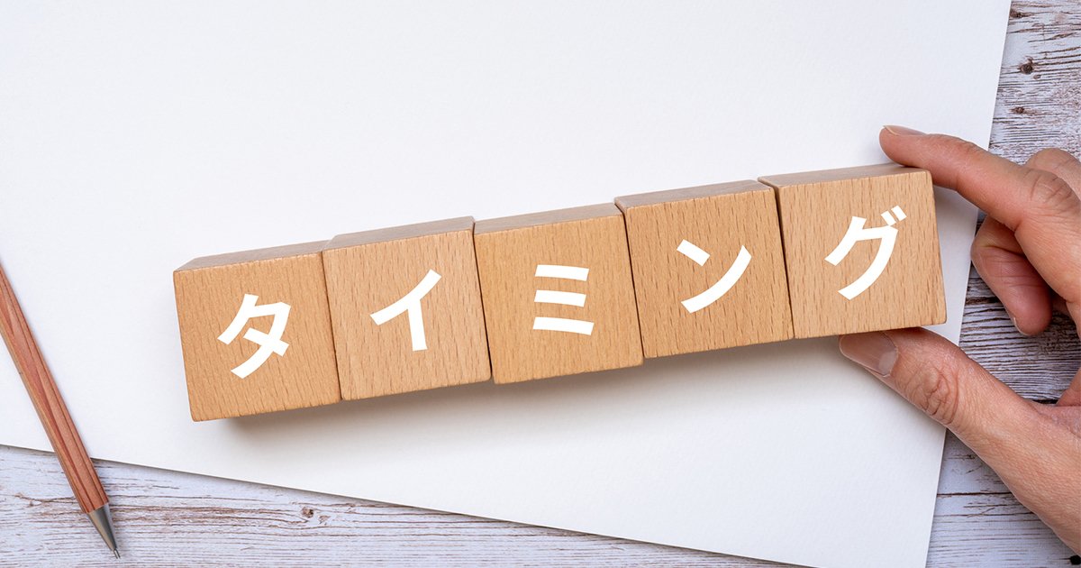 タイミングと書かれたブロック、ノート、ペン、手