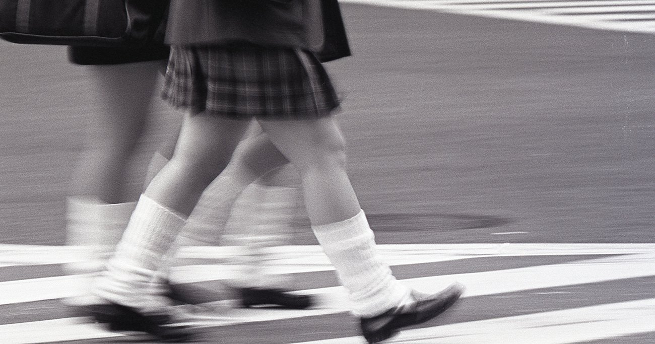 横断歩道を歩く制服姿の若者たち