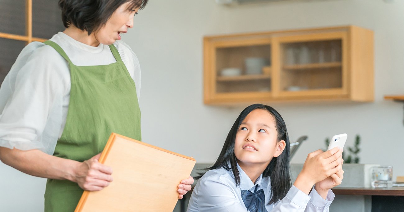 スマートフォンを手にした子どもと話す保護者