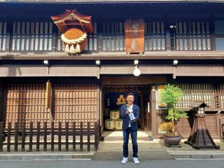国の登録有形文化財の蔵の前で、大定番の「家伝手造り」を手にする蔵元の渡邉久憲さん