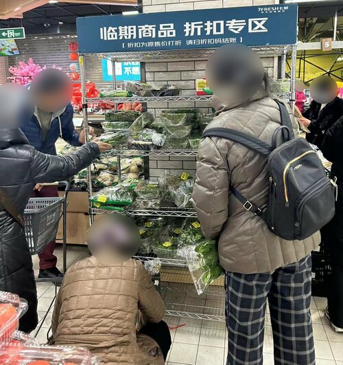 安売りコーナーで品定めをする人たち(七鮮)