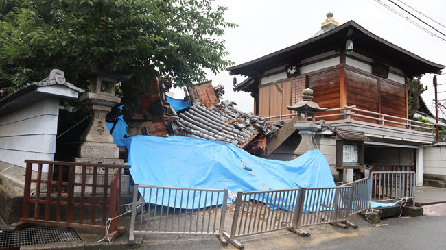 大阪北部地震でひっくり返った浄教寺の門。雨に備えてブルーシートがかけられていた