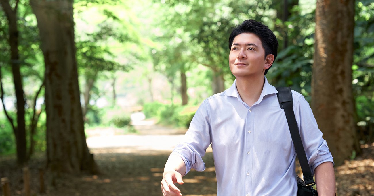 緑の多い公園を歩く男性