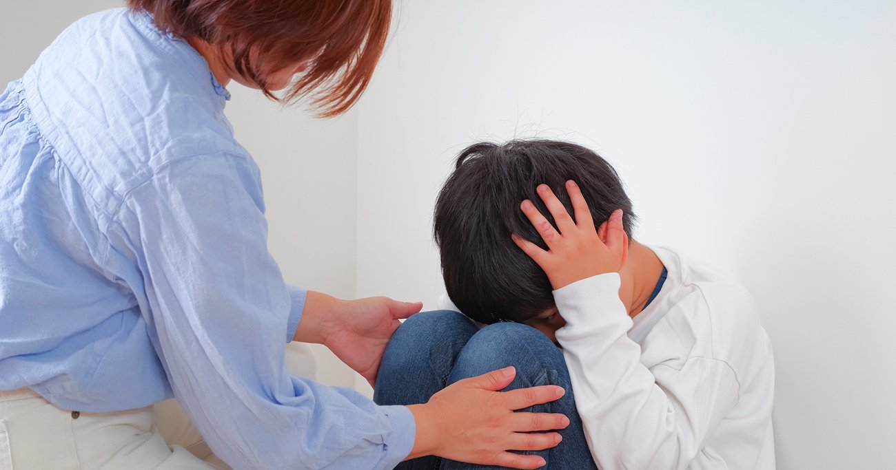 しゃがみ込んだ子どもに寄り添って声をかける保護者