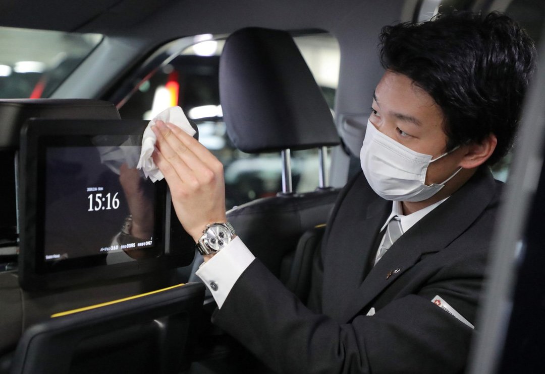 新型コロナウイルスの感染予防対策で、タクシー車内の消毒を行う担当者(2月16日撮影)