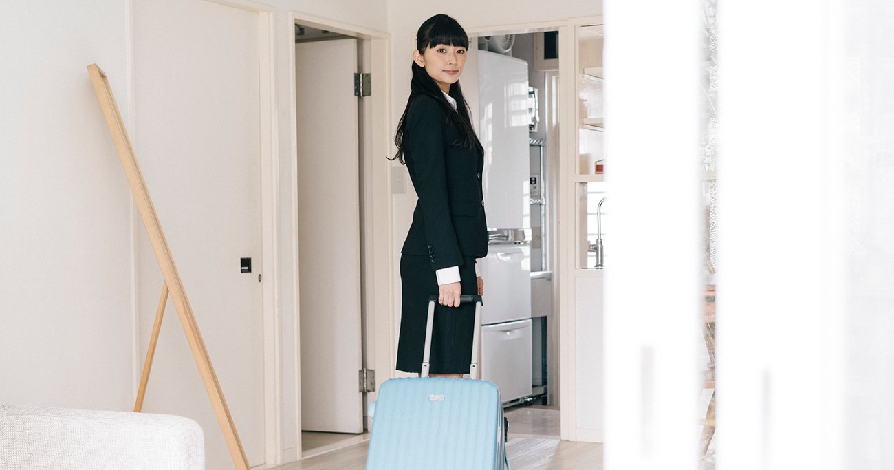 キャリーケースを持ち部屋を出る若い女性