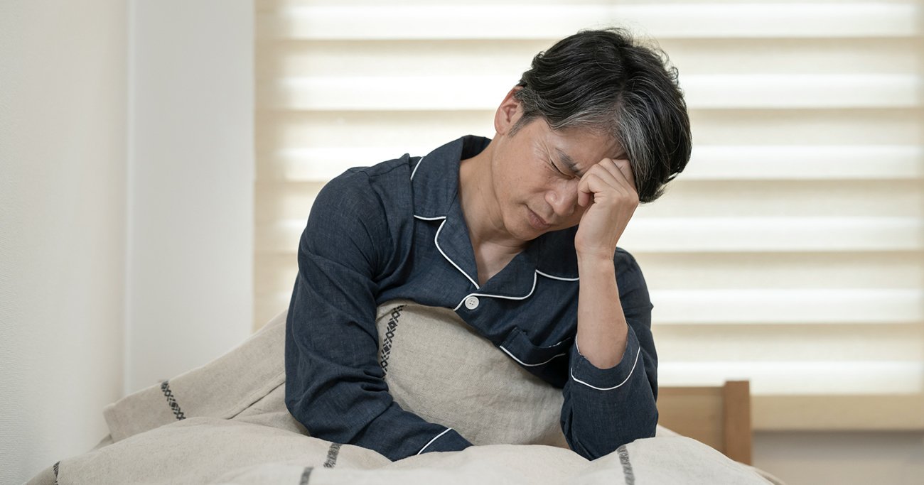 ベッドで頭を抱え体調不良を訴える男性