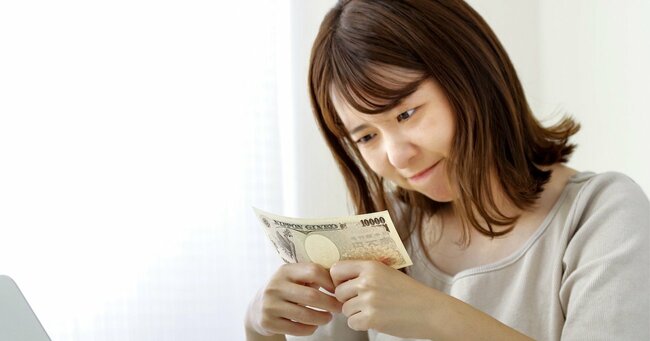 写真：1万円札を見つめる女性