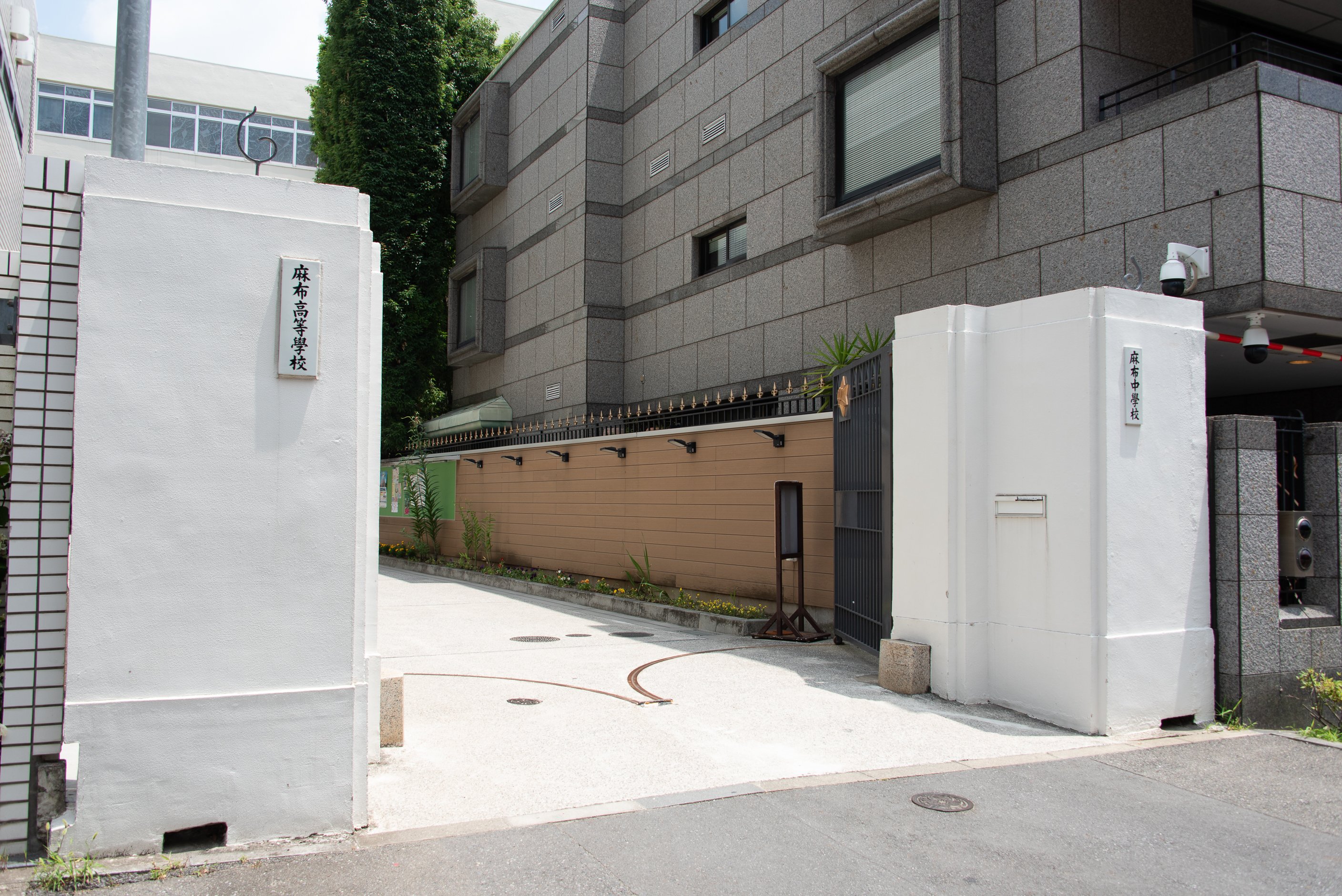 麻布の正門。道沿いの季節の花は園芸好きの平秀明校長の手による。右はカタール大使館