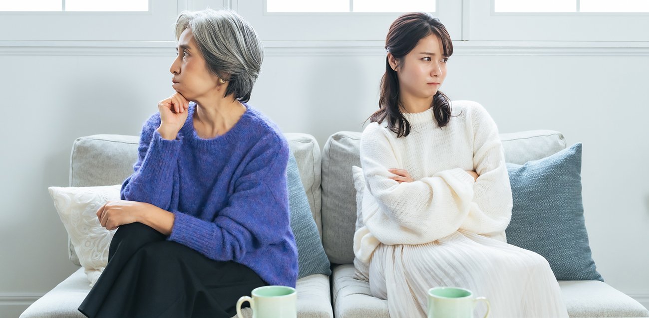 ソファで互いに目を合わせない年配女性と若い女性
