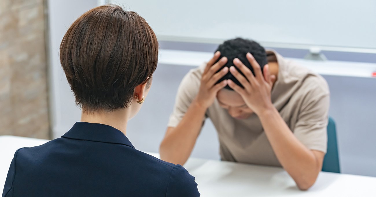 悩む黒人男性と面談する日本人女性スタッフ