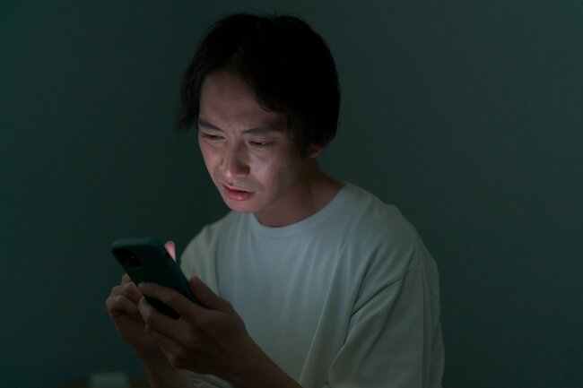 スマホを見て絶望した表情を浮かべる男性