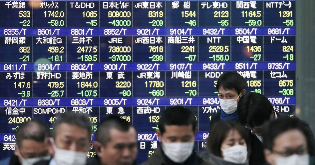 株価下落を示す株価ボードとマスクをする人々