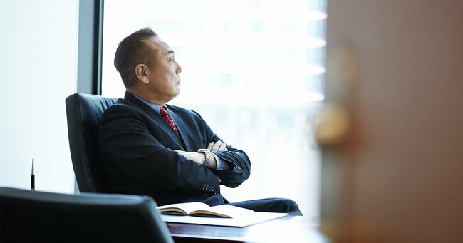 椅子に座り腕を組んで座る男性