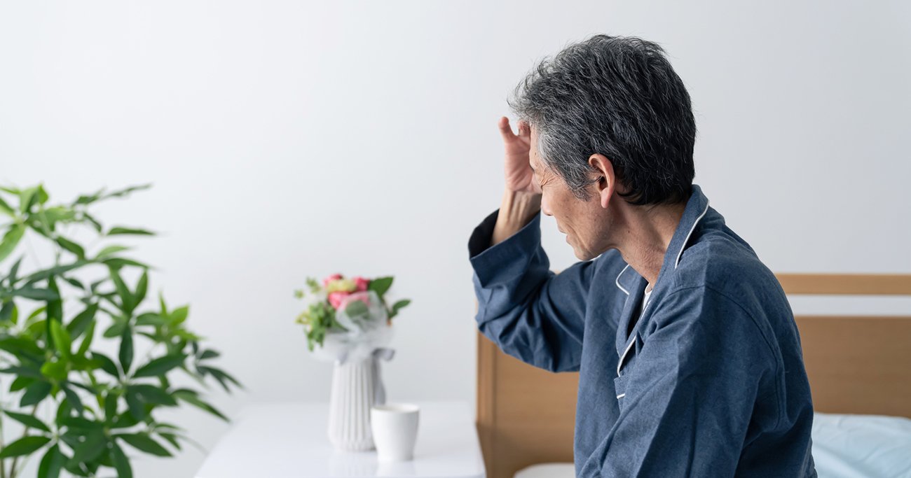 ベッドに座り不安そうにうつむく男性