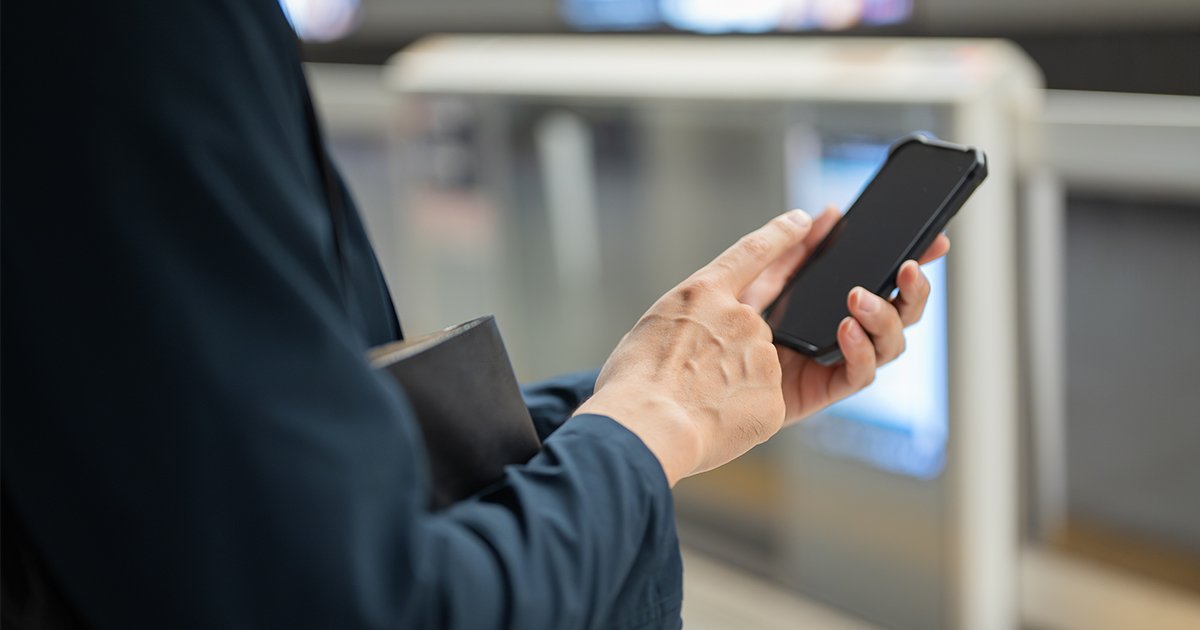 駅のホームでスマホを操作する人