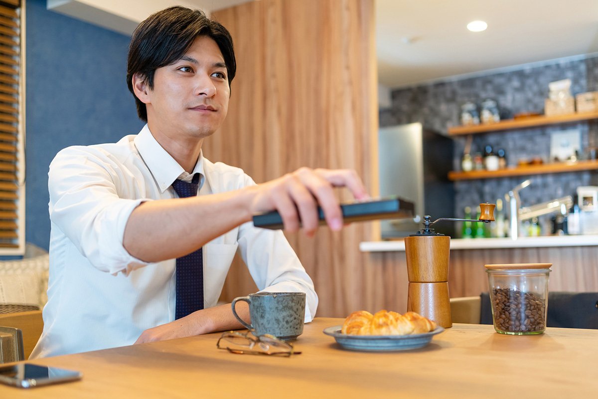 朝食時にテレビをつける男性