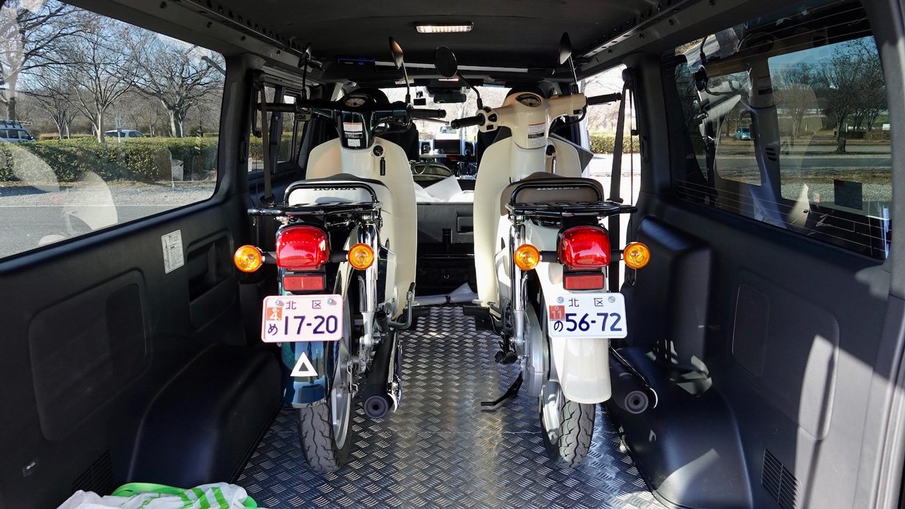 フェル号ハイエースに2台積みした様子。見た目はほぼ同じでも、新基準原付のLiteは白ナンバーで、原付二種のスーパーカブ110はピンクナンバーになる