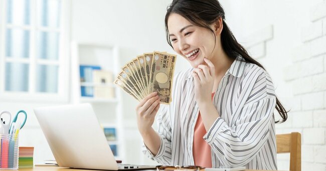 写真：1万円札を持って喜んでいる女性