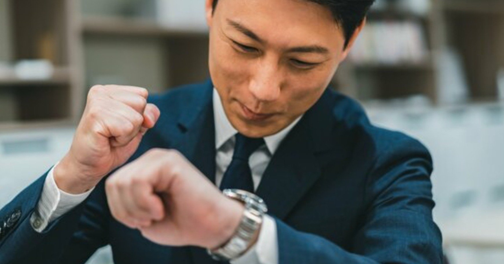 腕時計を見てガッツポーズをするビジネスパーソン