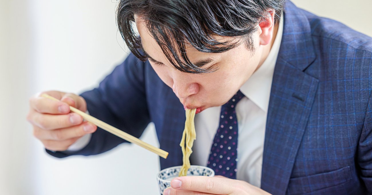 そばを食べるスーツ姿の男性