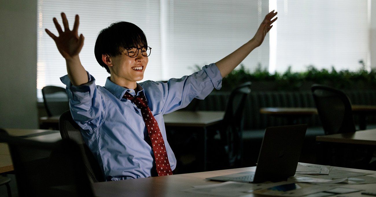 残業中のオフィスで、両手を広げながら笑顔を見せる男性社員