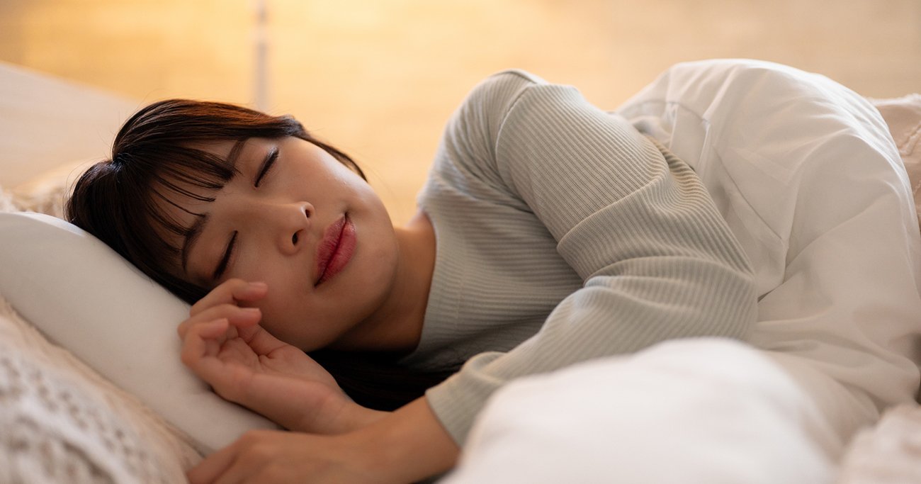 ベッドで横向きに眠りに入る女性