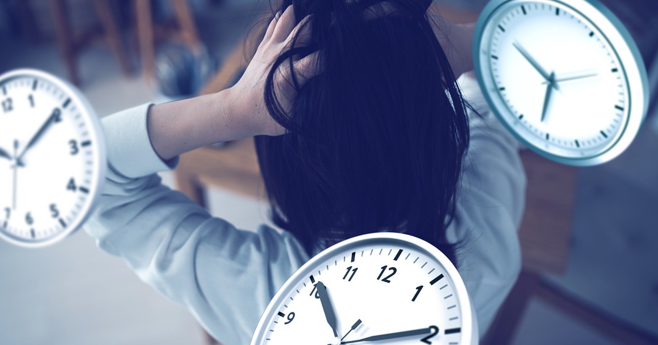 時計に囲まれて頭を抱える女性