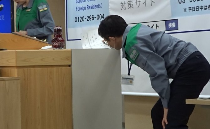 小池知事(左)に座席表を手渡す初宿理事。公務員は決して楽な仕事ではない