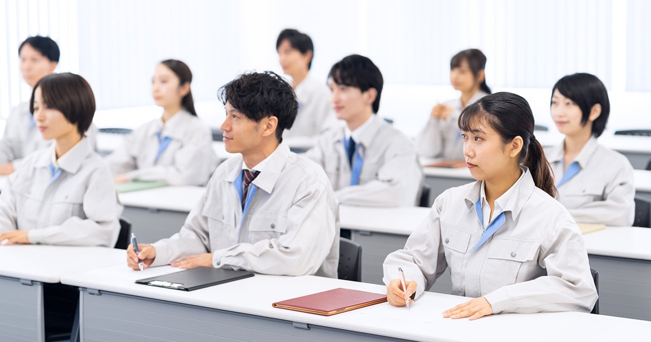 研修を受けながらメモを取る作業服姿の社員たち