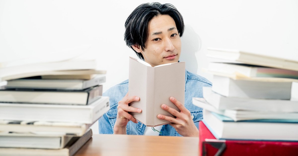 本に囲まれて読書する男性