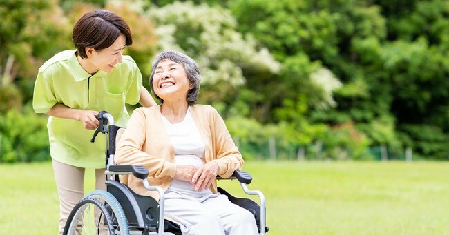 介護士と車椅子に座る高齢女性