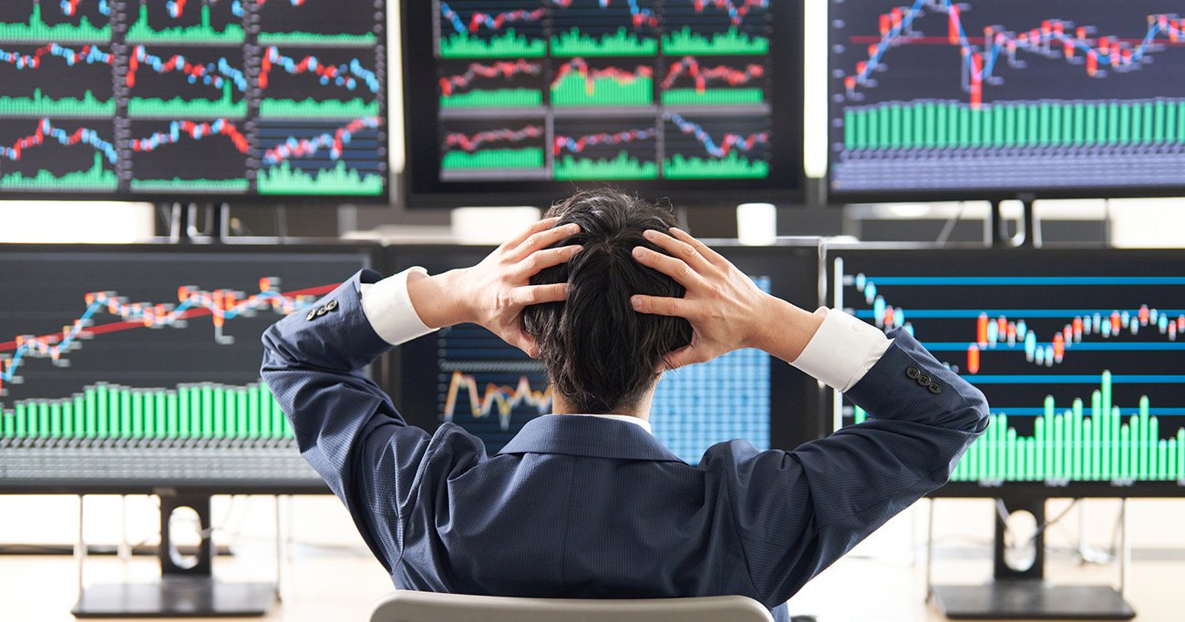 株価チャートを前に頭を抱える投資家の後ろ姿