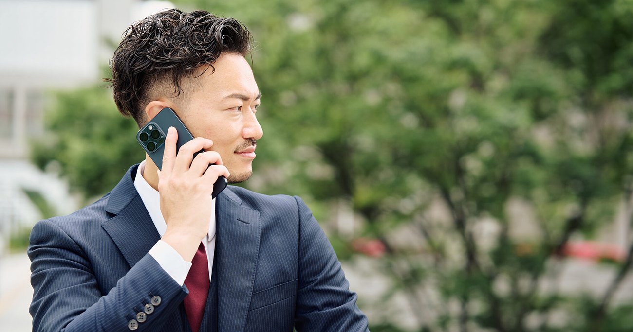 屋外で電話をする男性会社員