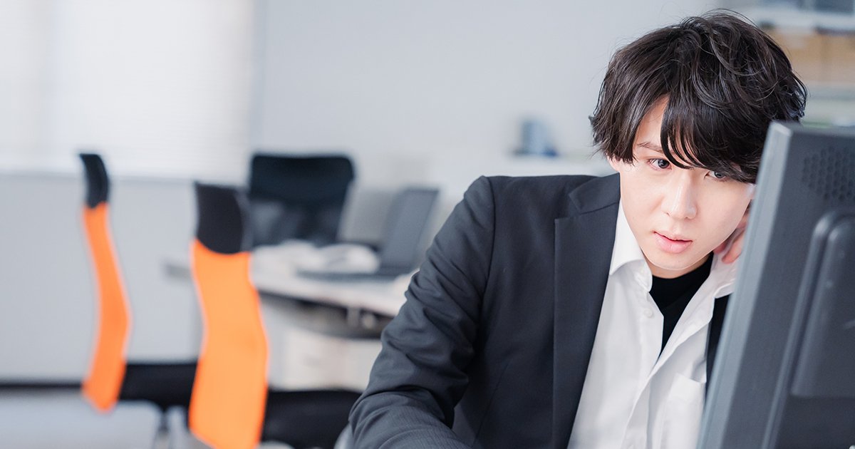 パソコンの前で考え込む若い男性