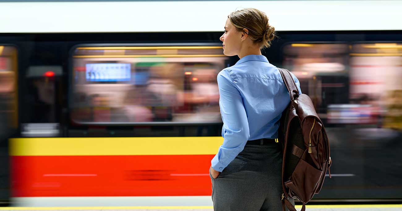 Woman with backpack standing at metro platform with moving train