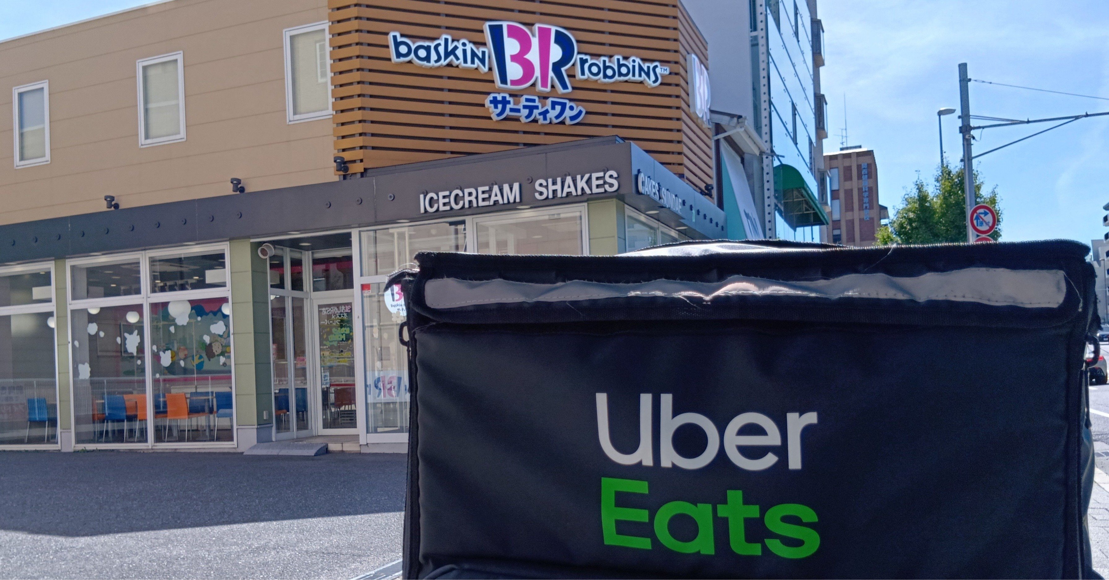ウーバーイーツ配達員のバッグとサーティワンアイスクリームの看板