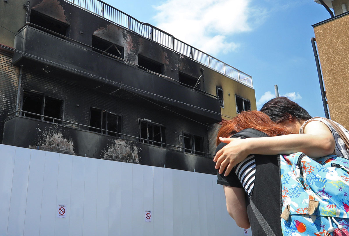 放火された「京都アニメーション」第1スタジオの前で涙ぐむ女性ら=25日、京都市伏見区