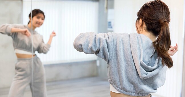 写真：ダンススタジオで鏡を見て踊る若い女性