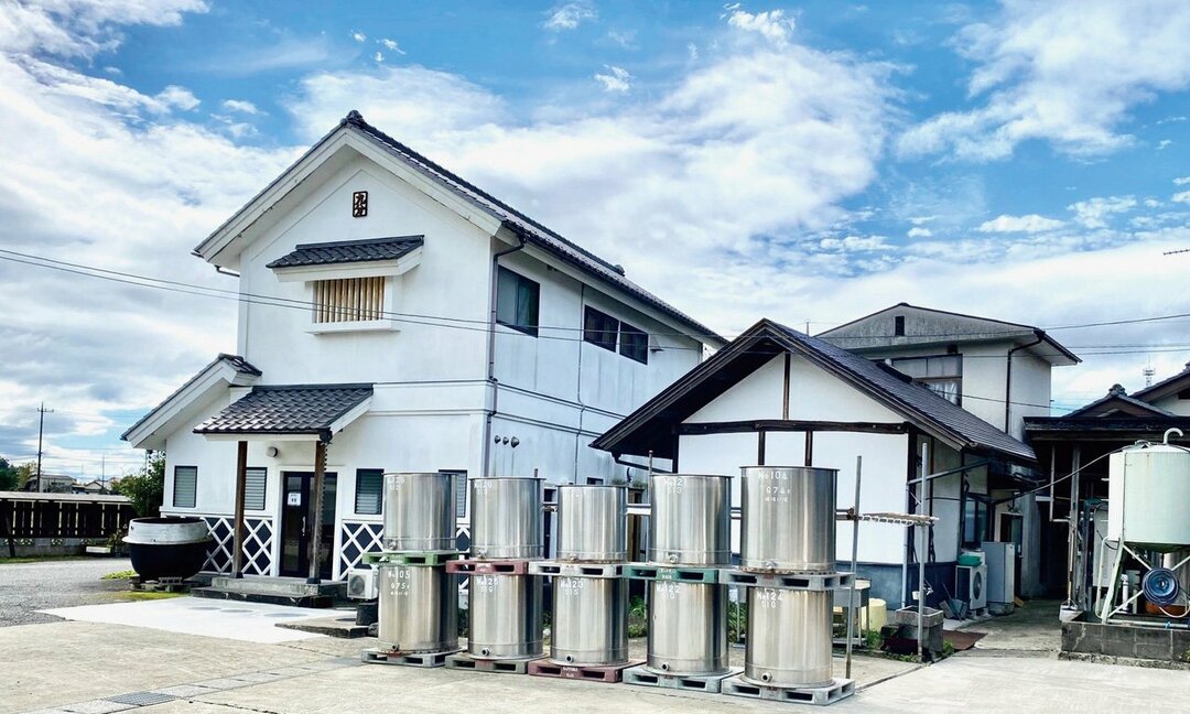 田んぼに囲まれ自然豊かな環境に立つ蔵。屋根の下の妻飾りには、九尾伝説に由来する屋号の九分の文字が