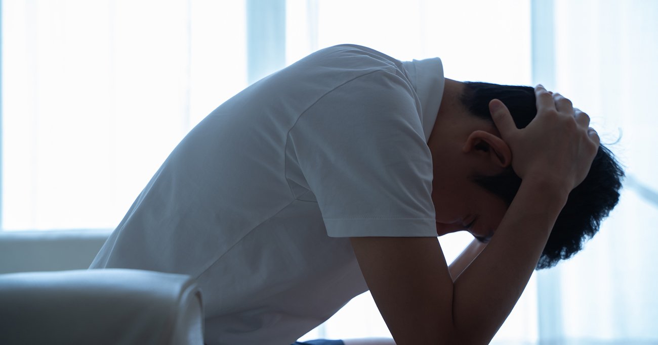 頭を抱えて落ち込む男性
