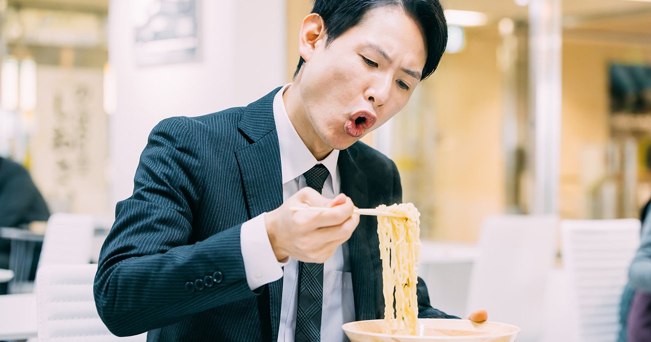ラーメンを食べるスーツ姿の男性