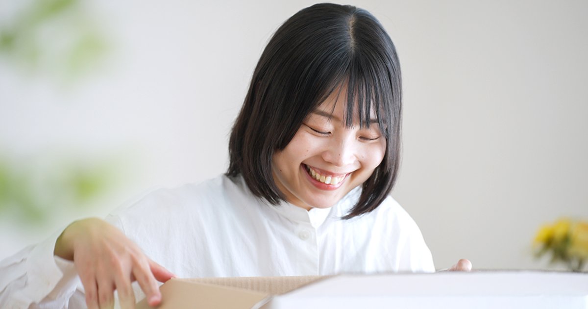 段ボールを開封する笑顔の女性