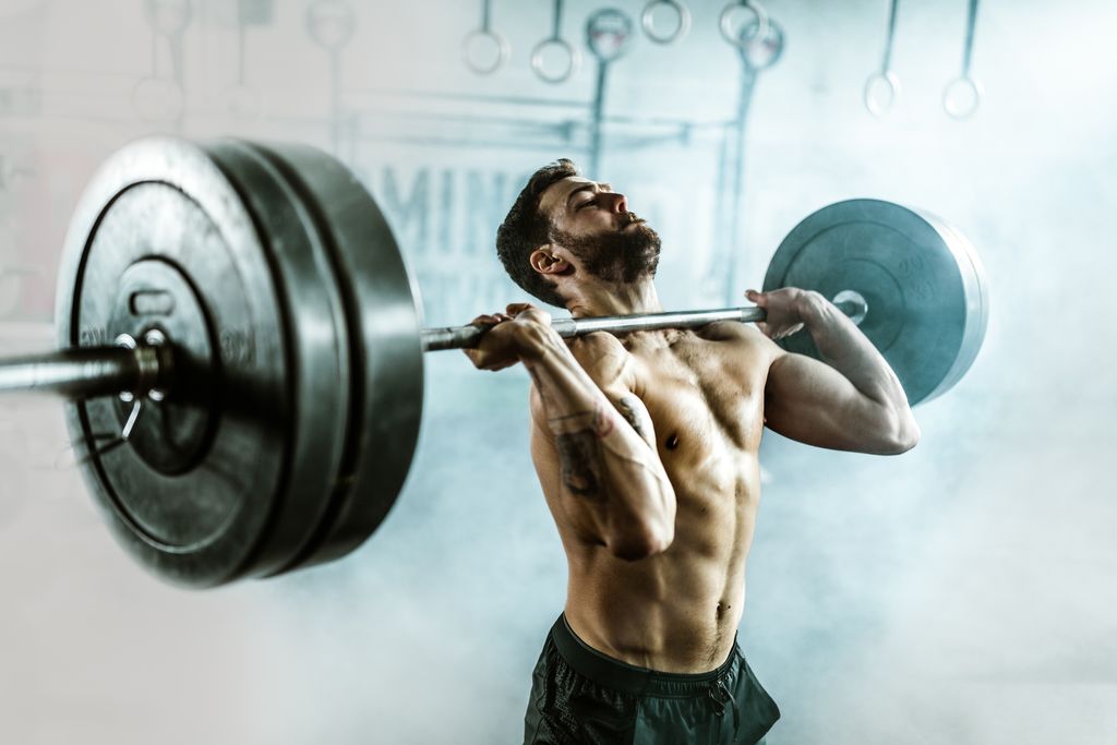 determined athletic man lifting heavy barbell in a gym