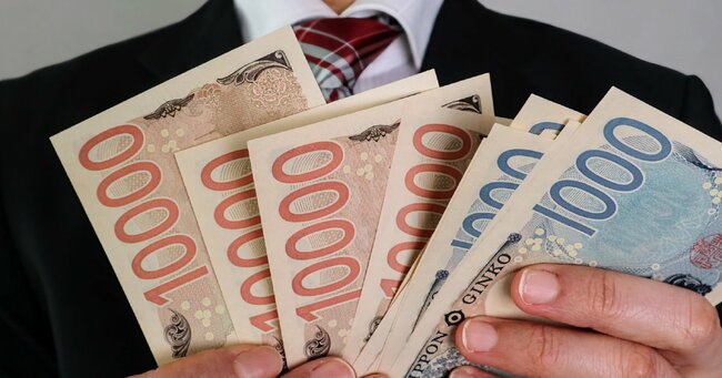 日本紙幣を手にしたスーツの男性
