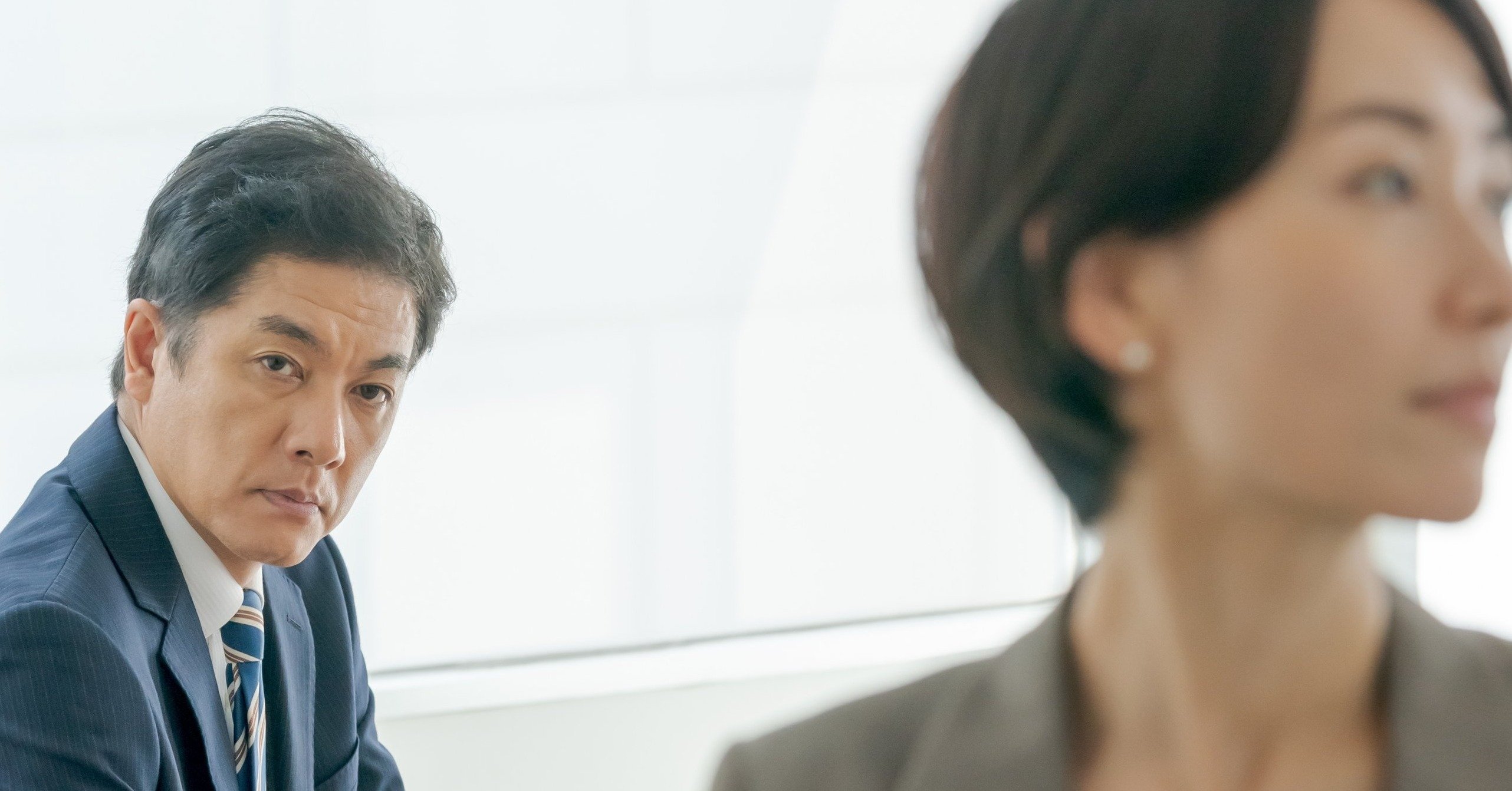 女性の後ろ姿を見つめる男性