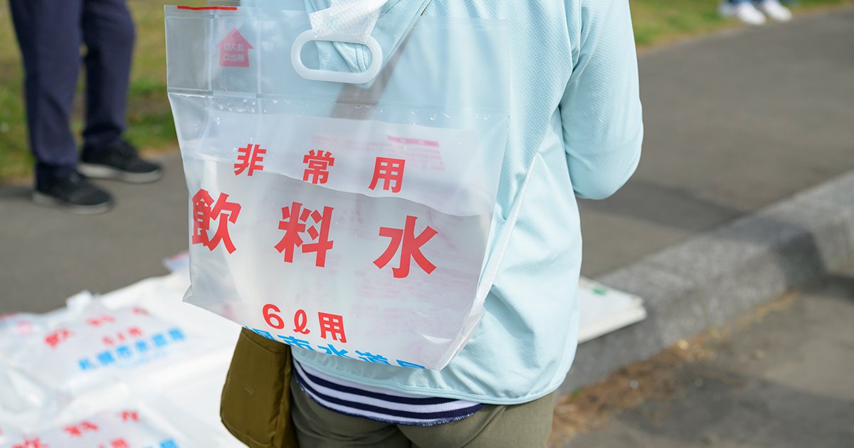 非常用飲料紙袋を背負う人物