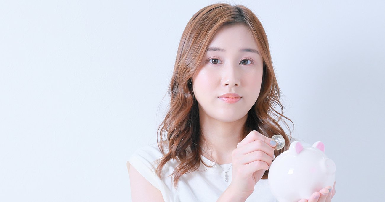 貯金箱に硬貨を入れる女性