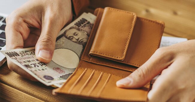 財布から日本紙幣を出す男性